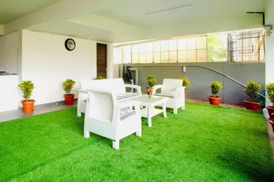 a room with white chairs and a table and grass at Elite Enclave - Tellus - 2BHK - Luxury Serviced Apartments in Mysore