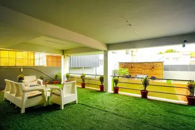 a patio with chairs and a table and green grass at Elite Enclave - Spark - 2BHK Luxury Serviced Apartment in Mysore