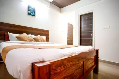 a bedroom with a large wooden bed with white sheets at Elite Enclave - Vento - 2BHK Luxury Serviced Apartments in Mysore