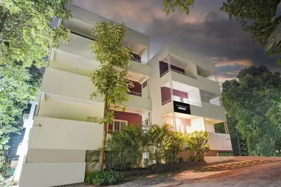 a white building with trees in front of it at Super Townhouse Hebbal Mysore in Mysore