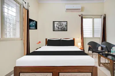 a bedroom with a bed and two chairs at Super Townhouse Hebbal Mysore in Mysore