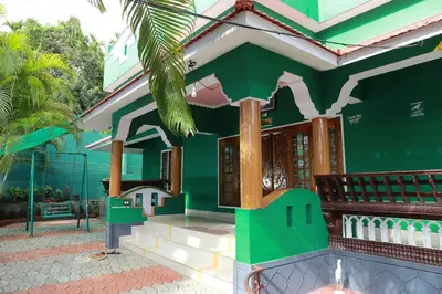 a green house with a palm tree in front of it at County Pep in Wayanad