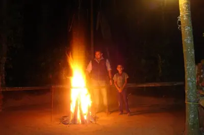 a man and a child standing next to a fire at County Pep in Wayanad