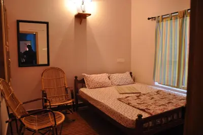 a bedroom with a bed and two chairs and a mirror at County Pep in Wayanad