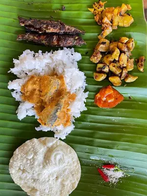 a green plate with rice and other foods on a banana leaf at Dhara Dhvani Getaway Homes in Tindummal