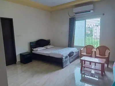 a bedroom with a bed and a window and a table at Govinda Krishna Comforts in Mysore