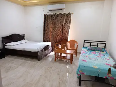 a bedroom with two beds and a table and a chair at Govinda Krishna Comforts in Mysore