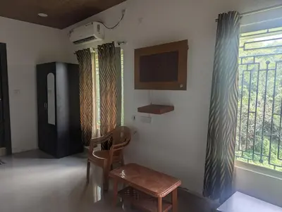 a living room with a chair and a window at Govinda Krishna Comforts in Mysore