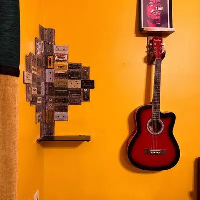 a guitar hanging on a wall with a collage of stickers at Rastafari - The Backpackers Hostel in Ooty