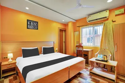 a bedroom with a bed and a desk and a window at Super Collection O Kushal Nagar Near KSRTC Bus Stand in Madikeri