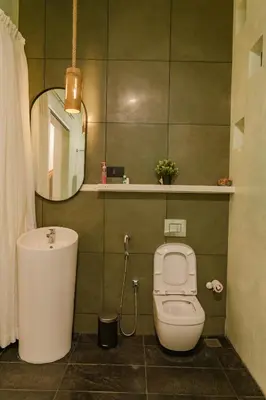 a bathroom with a toilet and a sink and a mirror at Thira Beach Home in Thanniyam
