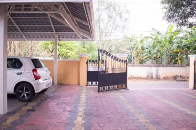 a white car parked under a building with a gate at Jaalakam Retreat in Trichūr