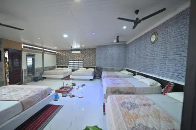 a room with four beds and a brick wall at MysticGreens Guest House! in Kushālnagar