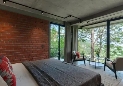 a bedroom with a brick wall and a large bed at LohonoStays Villa Amani 8A in Coonoor