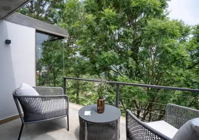 a patio with wicker chairs and a table on a balcony at LohonoStays Villa Amani 8A in Coonoor