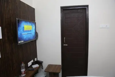 a bathroom with a door and a tv on a wall at Kandhaguru Residency in Palani
