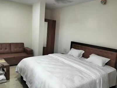 a bedroom with a large white bed and a couch at Amma Inn Elegance Suites and Apartments in Mysore
