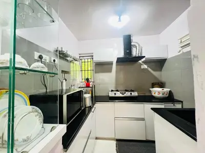 a kitchen with white cabinets and black counters at Teyt's White Home - 3 bedroom Villa in Ooty