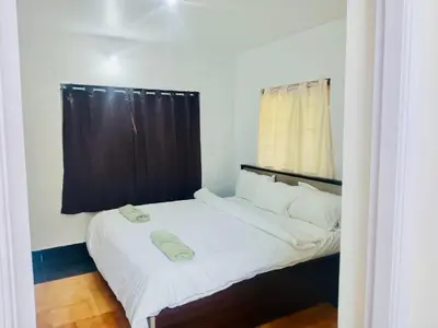 a small bedroom with a bed with a black curtain at Teyt's White Home - 3 bedroom Villa in Ooty