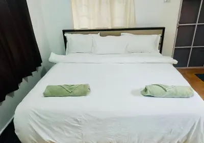 a large white bed with two green pillows on it at Teyt's White Home - 3 bedroom Villa in Ooty