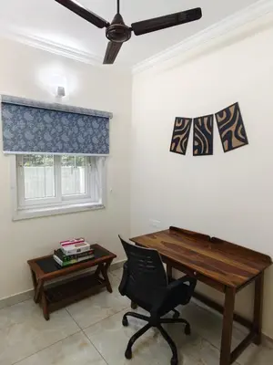 a desk and a chair in a room with a window at 7 Elysee Homestay - Onyx - Premium 3BHK Family Flat in Trichūr