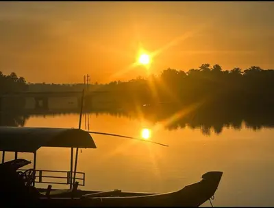 a boat on a lake with the sun setting at Green Island Homestay Riverside in Kozhikode