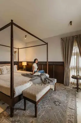 a woman sitting on a bed in a bedroom at LohonoStays Villa Lansdowne in Coonoor
