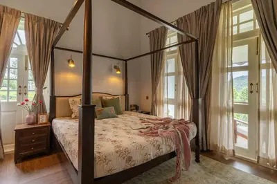 a bedroom with a canopy bed and windows at LohonoStays Villa Lansdowne in Coonoor
