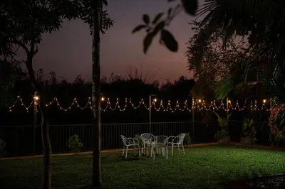 a table and chairs in a backyard with lights at Swasth The Riviera Lovedale in Nilambūr