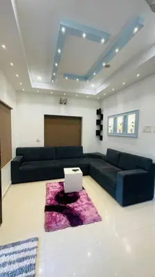 a living room with two black couches and a purple rug at Swasth The Riviera Lovedale in Nilambūr