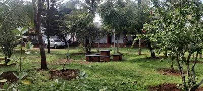 a park with two benches and trees and a house at Aastha homestay in Mysore