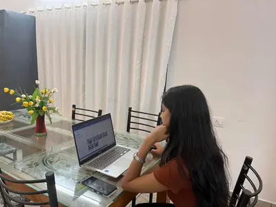 a woman sitting at a table with a laptop computer at Crystal Riverview Homestay in Kuttampuzha