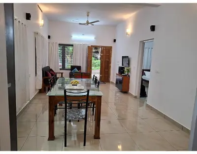 a dining room and living room with a table and chairs at Crystal Riverview Homestay in Kuttampuzha