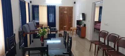 a dining room with a table and chairs and a living room at Crystal Riverview Homestay in Kuttampuzha