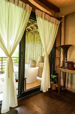a bedroom with a tub and a window with curtains at The Soul Marayoor Mudhouse - Munnar in Marayoor