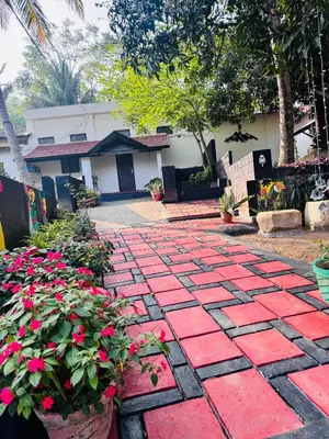 a garden with a red stone pathway with flowers at Mountain valley in Attappādi