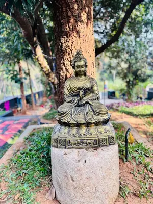 a statue sitting next to a tree in a park at Mountain valley in Attappādi