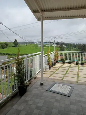 a porch with potted plants and a white railing at Haze cottage- MA Cottage in Ooty