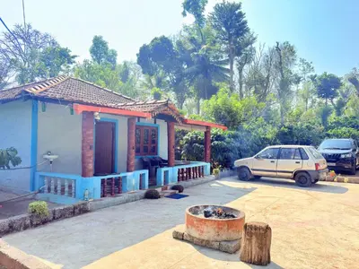 a car parked in front of a small house at Preetham Homestay in Kushālnagar