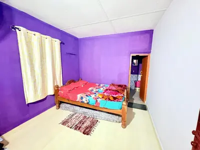 a bedroom with purple walls and a bed at Preetham Homestay in Kushālnagar