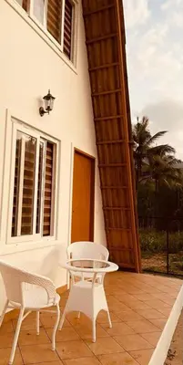 a patio with two chairs and a table and a building at Hill View 'A'Frame Villa Wayanad in Vythiri