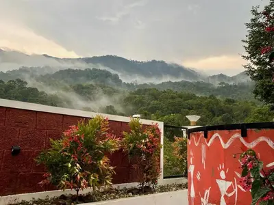a room with a view of a mountain with smoke at Hill View 'A'Frame Villa Wayanad in Vythiri