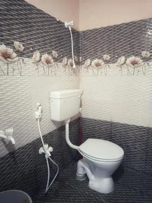 a bathroom with a toilet and flowers on the wall at Coconut Grove villa by Shivalaya Stays in Alāndurai