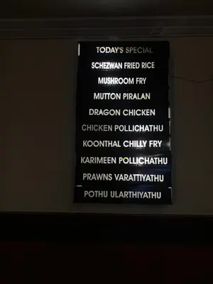 a sign with white writing on a wall at Maharani Hotel in Kozhikode