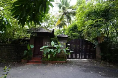 a gate to a house with a fence and trees at Illam Heritage inn Bungalow l 4 BHK in Guruvāyūr