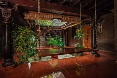 a room with a wooden table and some plants at Illam Heritage inn Bungalow l 4 BHK in Guruvāyūr