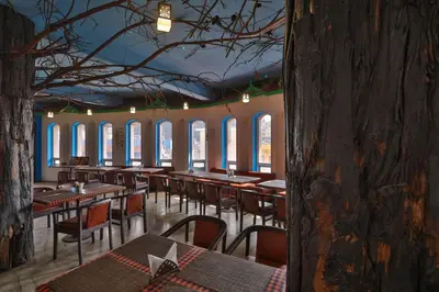 a dining room with tables and chairs and windows at Devi Enterprises - Hotel Khems in Ooty