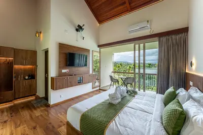 a bedroom with a large bed and a balcony at Theyila Wayanad Premium Pool Resort in Sultan Bathery