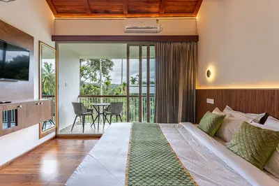 a bedroom with a large bed and a balcony at Theyila Wayanad Premium Pool Resort in Sultan Bathery