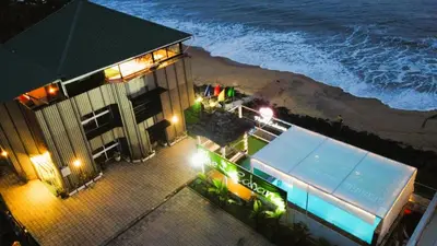 a building on the beach at night with the ocean at The Cabana in Cherai Beach